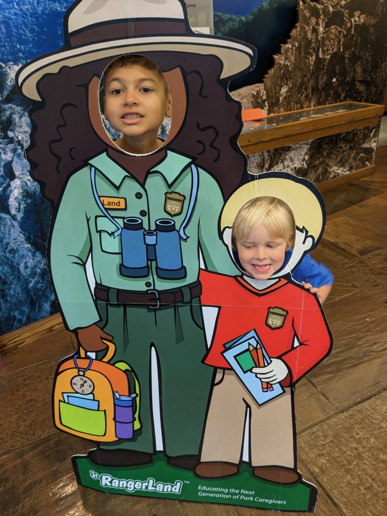 Liam and Madison posing behind a silhouette of a park ranger and child.